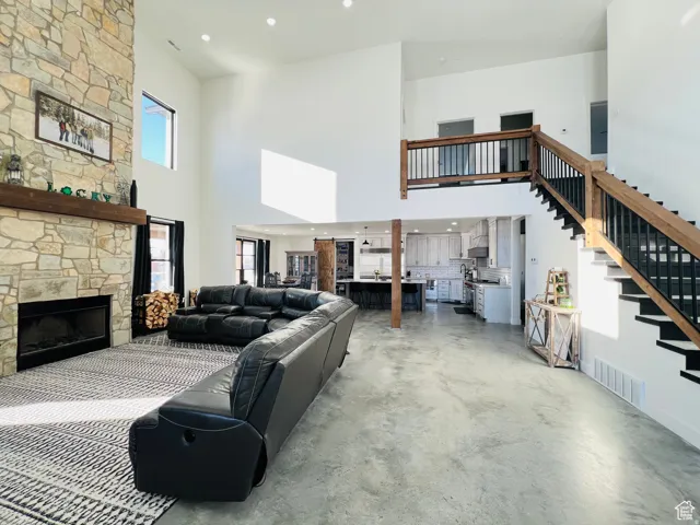 Living area featuring recessed lighting, concrete flooring, a high ceiling, and a fireplace