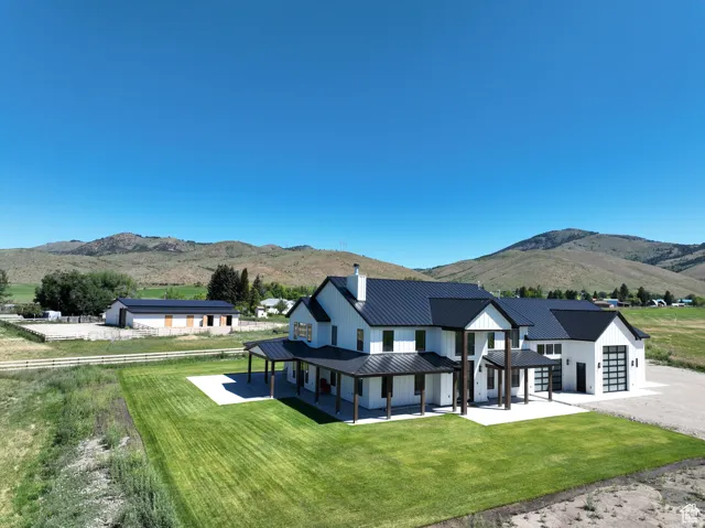 Back of property with a mountain view, a lawn, a garage, a chimney, and a metal roof