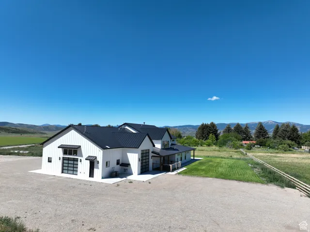 View of front of home with a view of countryside, a mountain view, board and batten siding, a metal roof, and driveway