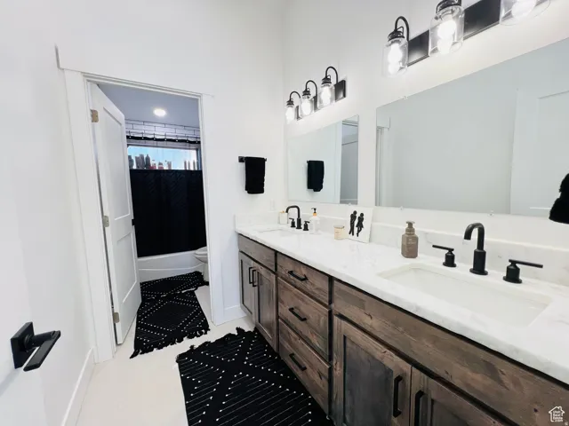 Bathroom with double vanity and shower / bath combination with curtain