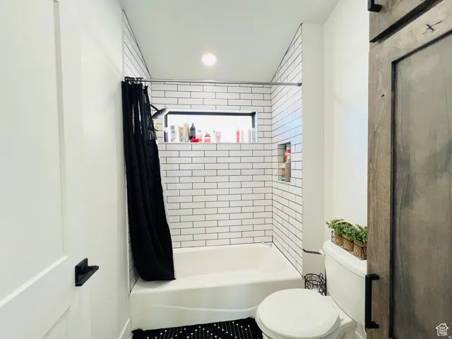 Bathroom featuring toilet and shower / bath combo with shower curtain