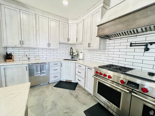 Kitchen with stainless steel appliances, light stone countertops, concrete flooring, recessed lighting, and backsplash