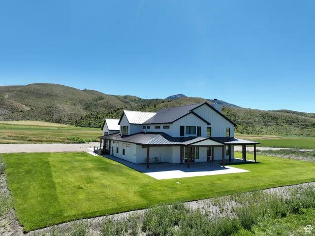 Rear view of property with a metal roof, a mountain view, a yard, and a patio area