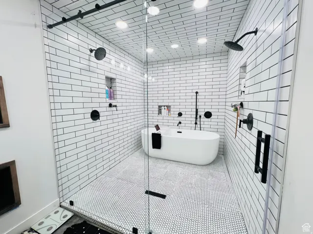 Full bathroom with a stall shower, a freestanding bath, and tile walls