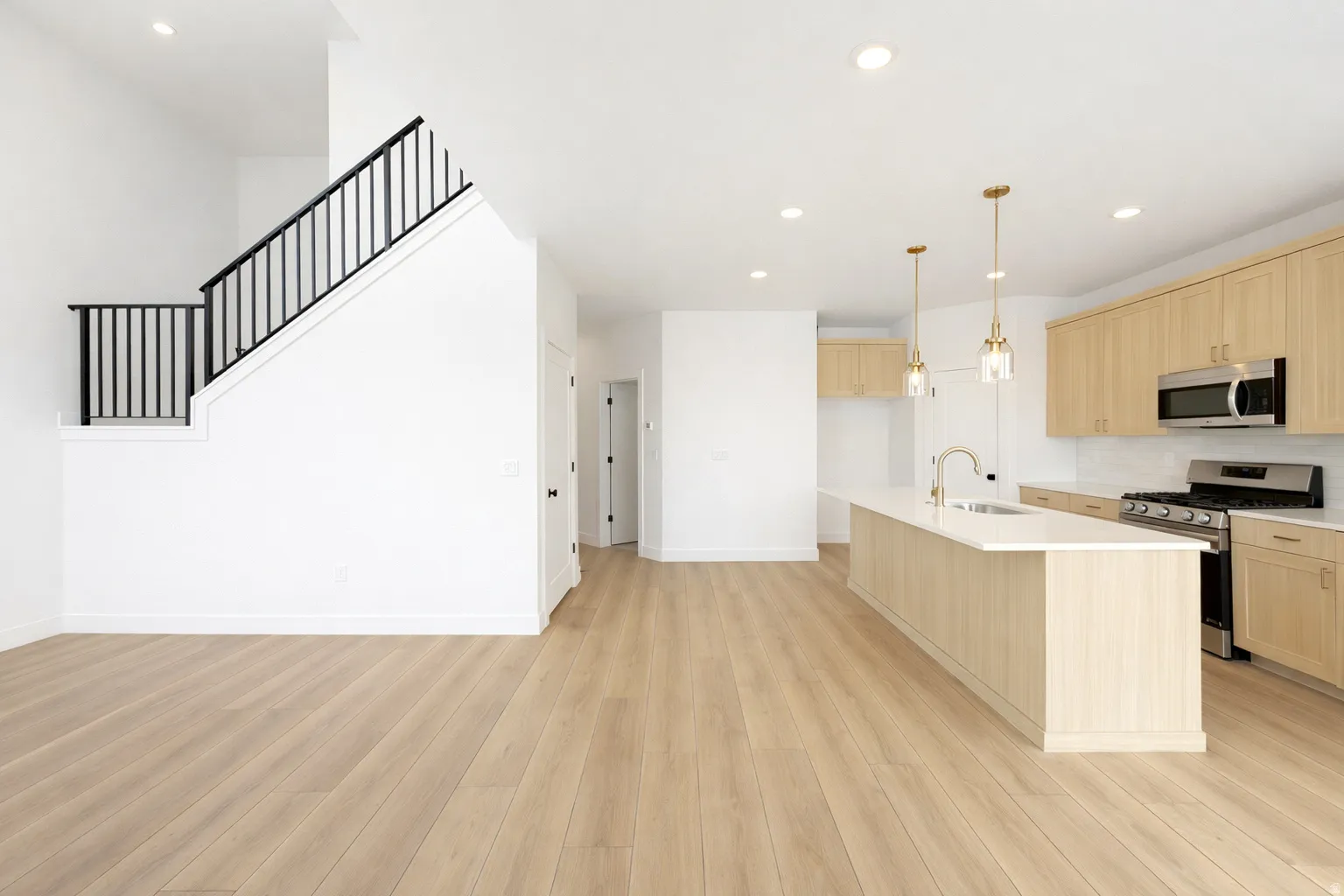 Kitchen featuring light wood finish cabinets, stainless steel appliances, open floor plan, and light wood-style flooring