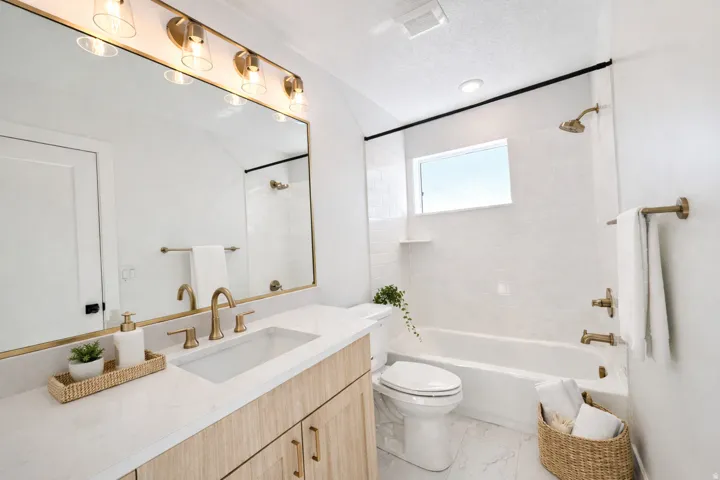 Full bathroom featuring vanity, bathtub / shower combination, light marble finish floors, and a textured ceiling