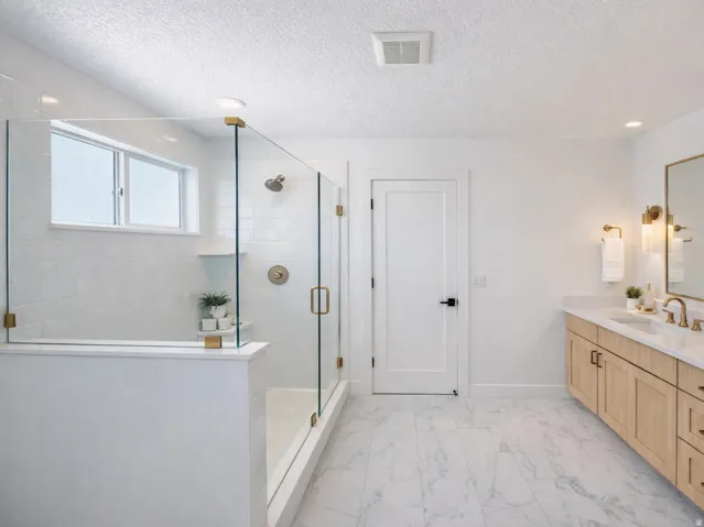 Full bath featuring vanity, a textured ceiling, a shower stall, light marble finish flooring, and recessed lighting