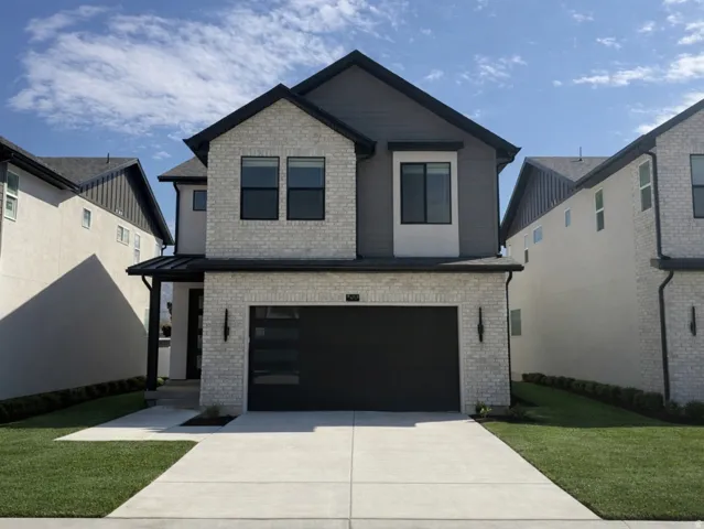 View of front of home featuring brick siding, a front yard, driveway, and an attached garage
