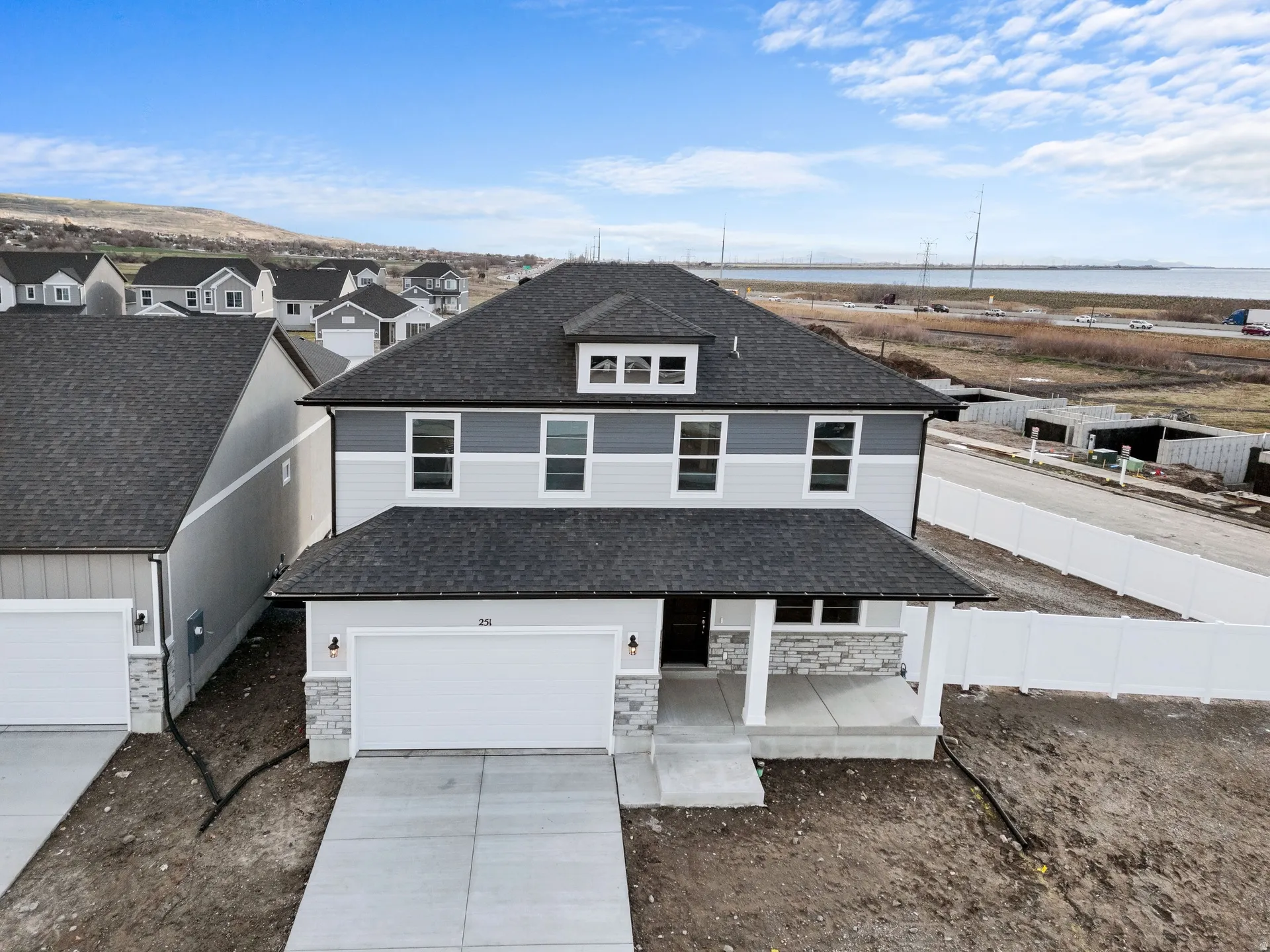View of front of house with a porch, stone siding, concrete driveway, and a shingled roof
