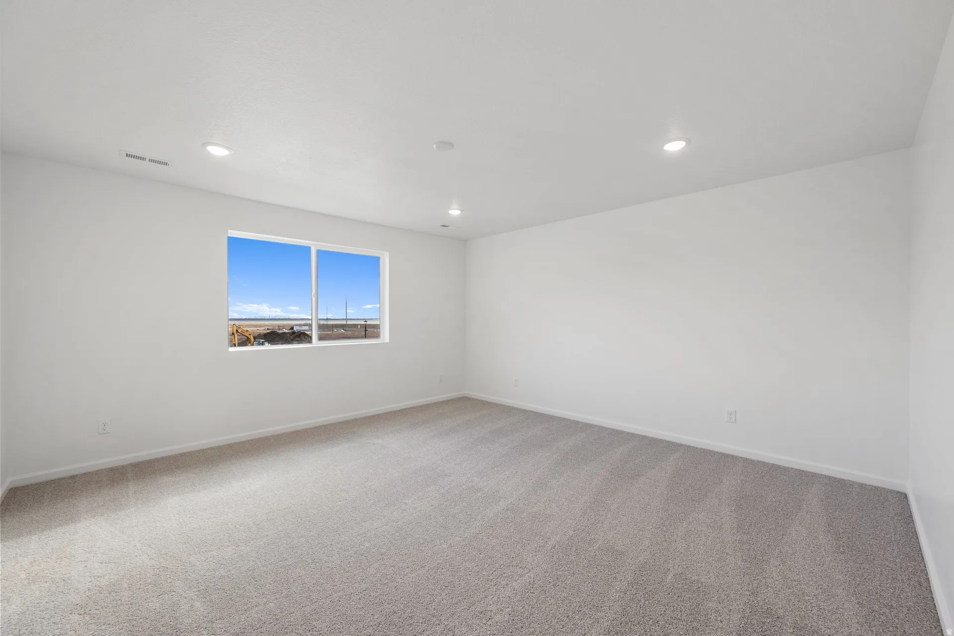 Primary bedroom with light carpet and recessed lighting