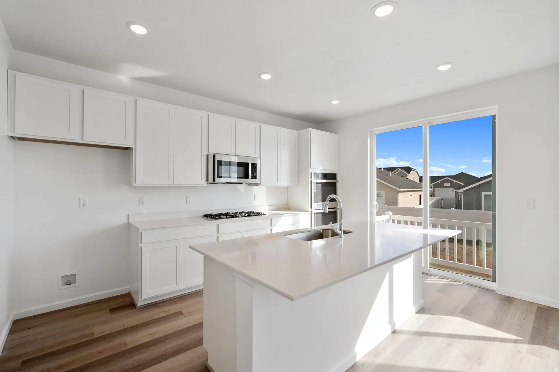 Kitchen featuring white cabinetry, light wood-style flooring, a center island with sink, recessed lighting, and stainless steel appliances