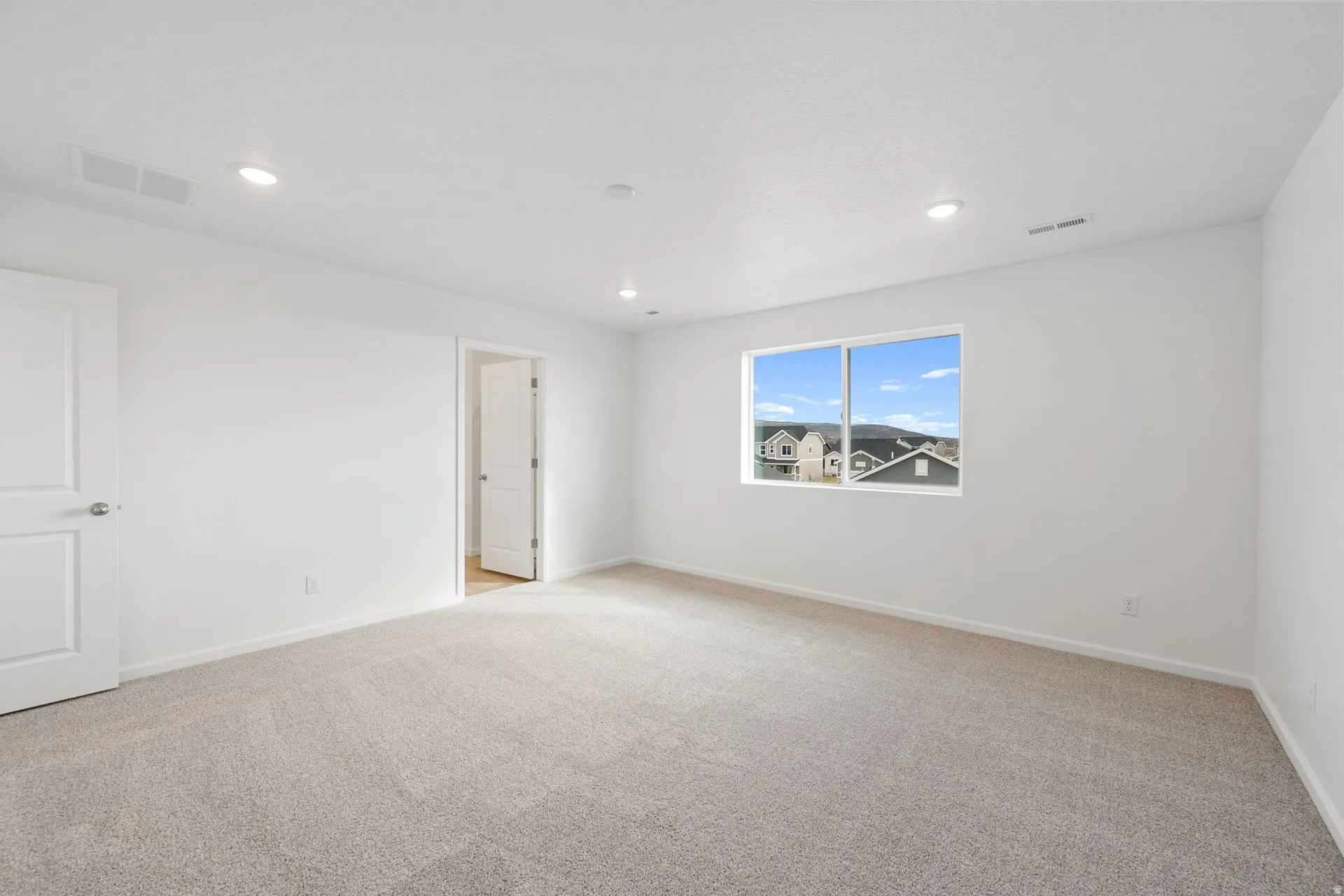 Primary bedroom featuring light carpet and recessed lighting
