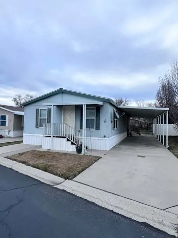 Manufactured / mobile home featuring an attached carport, driveway, and covered porch