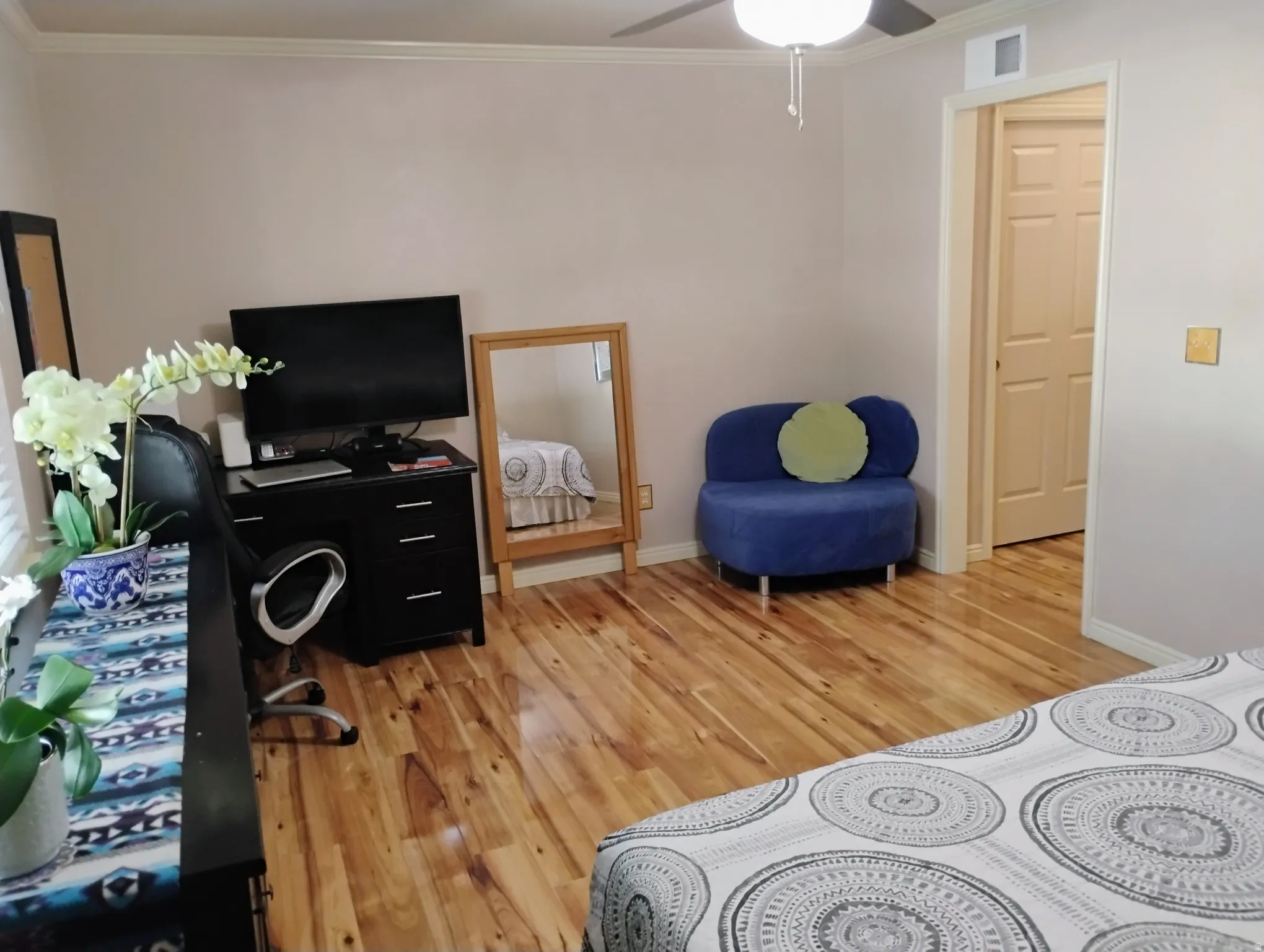 Bedroom with light wood finished floors, ornamental molding, and a ceiling fan