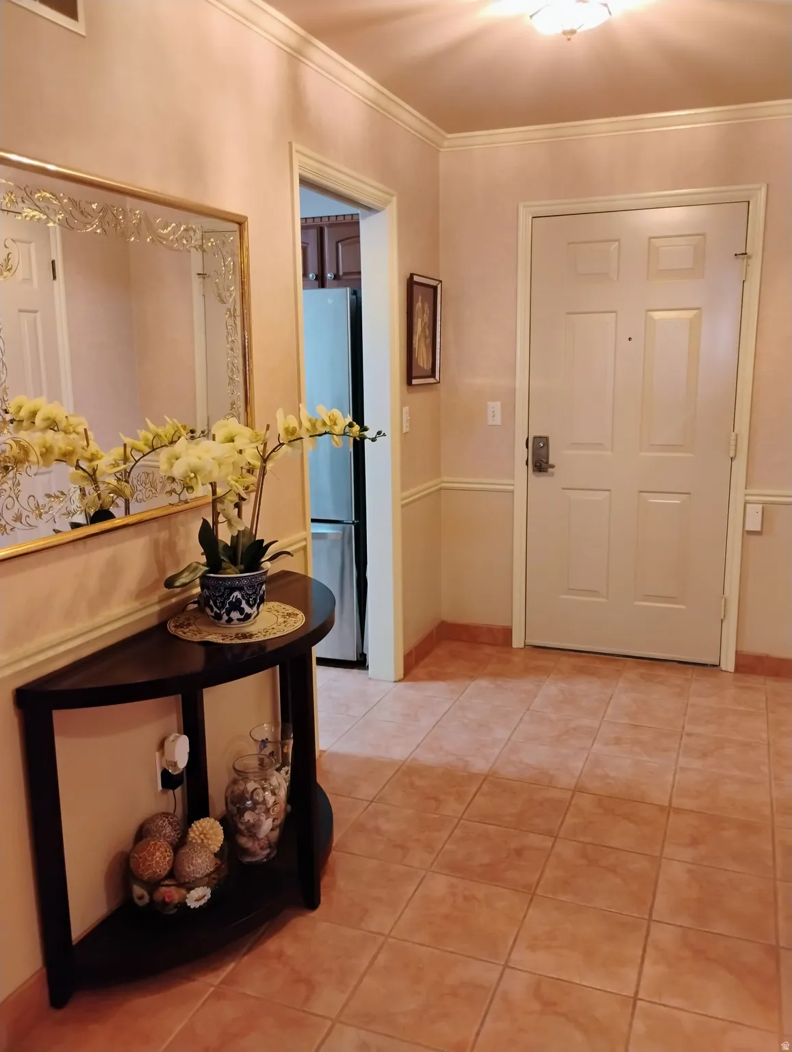 Entryway featuring light tile patterned floors and crown molding
