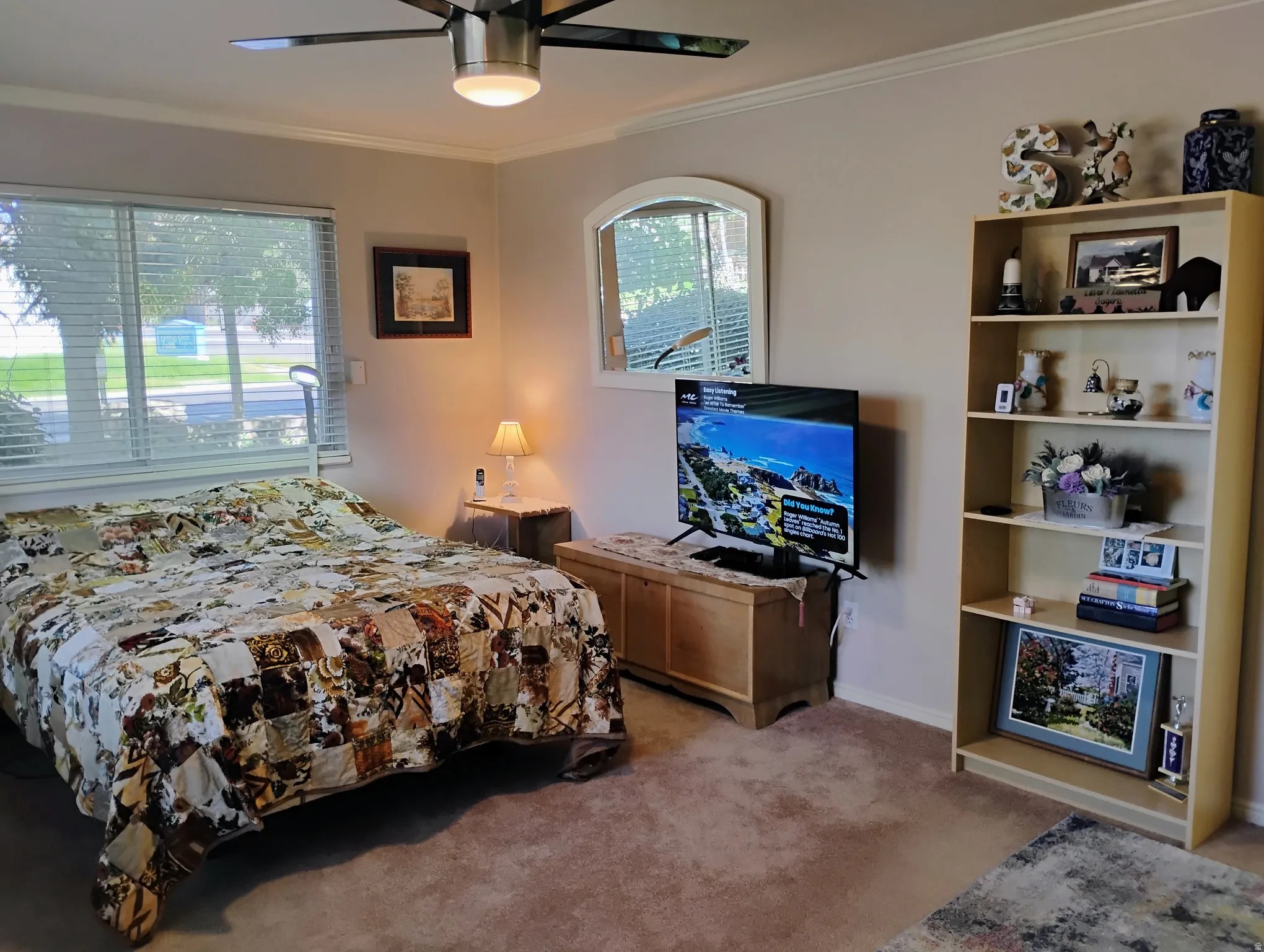 Bedroom with light colored carpet, crown molding, and a ceiling fan