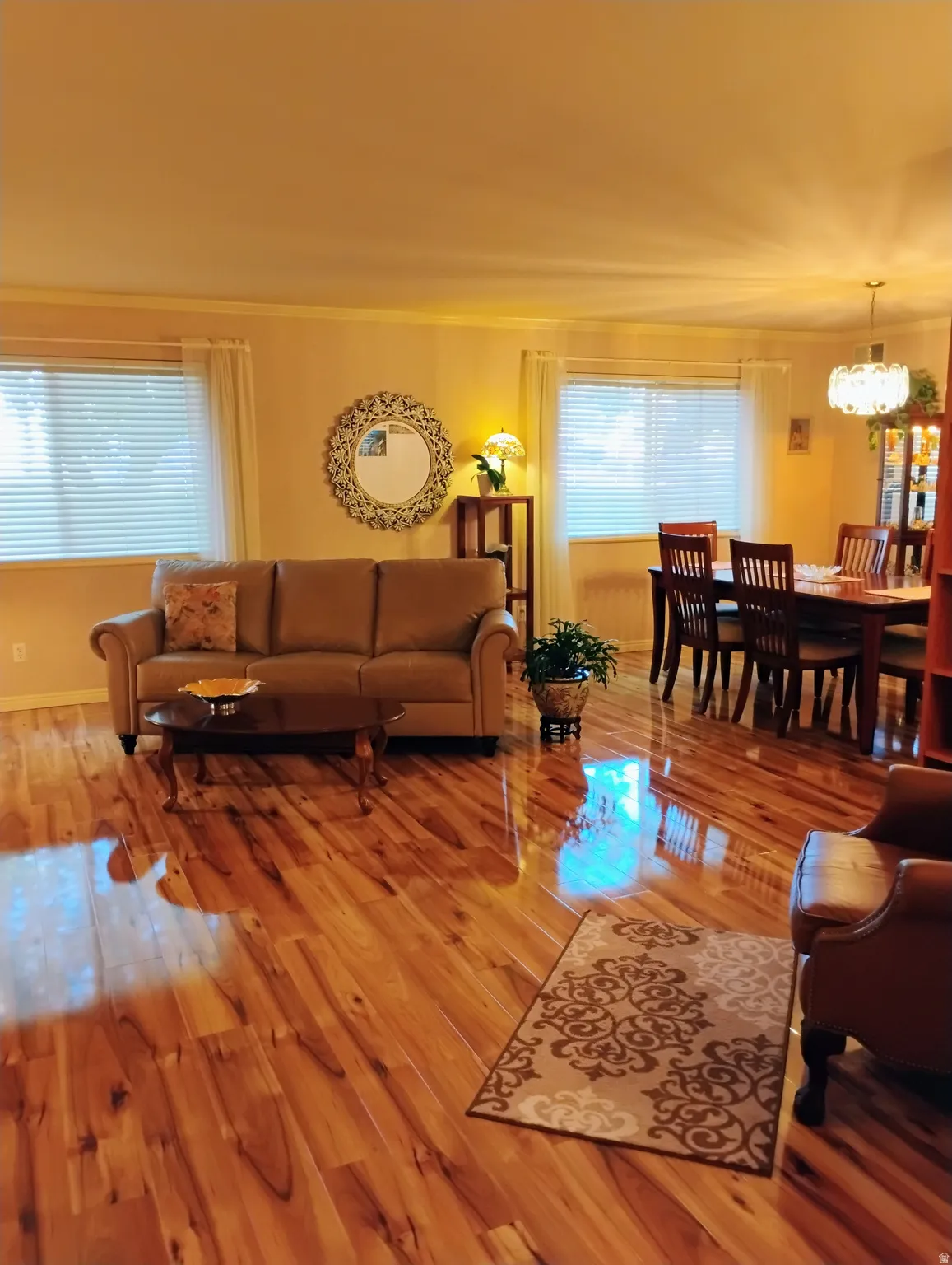 Living area with hardwood / wood-style floors, suspended lighting, and crown molding