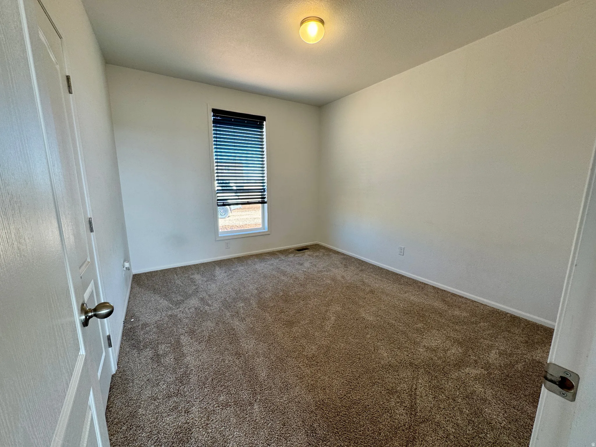 Carpeted empty room featuring baseboards and a textured ceiling