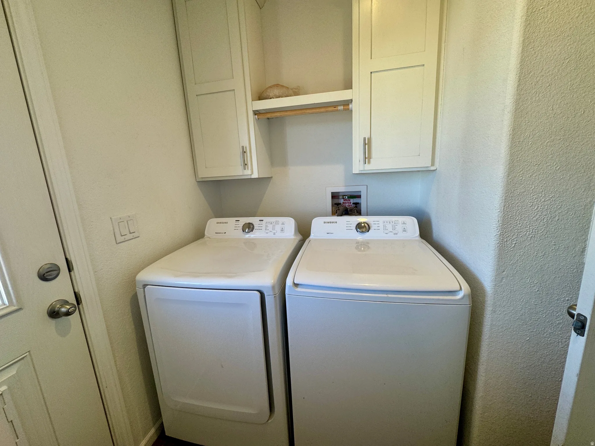 Laundry area with washing machine and dryer, a textured wall, and cabinet space