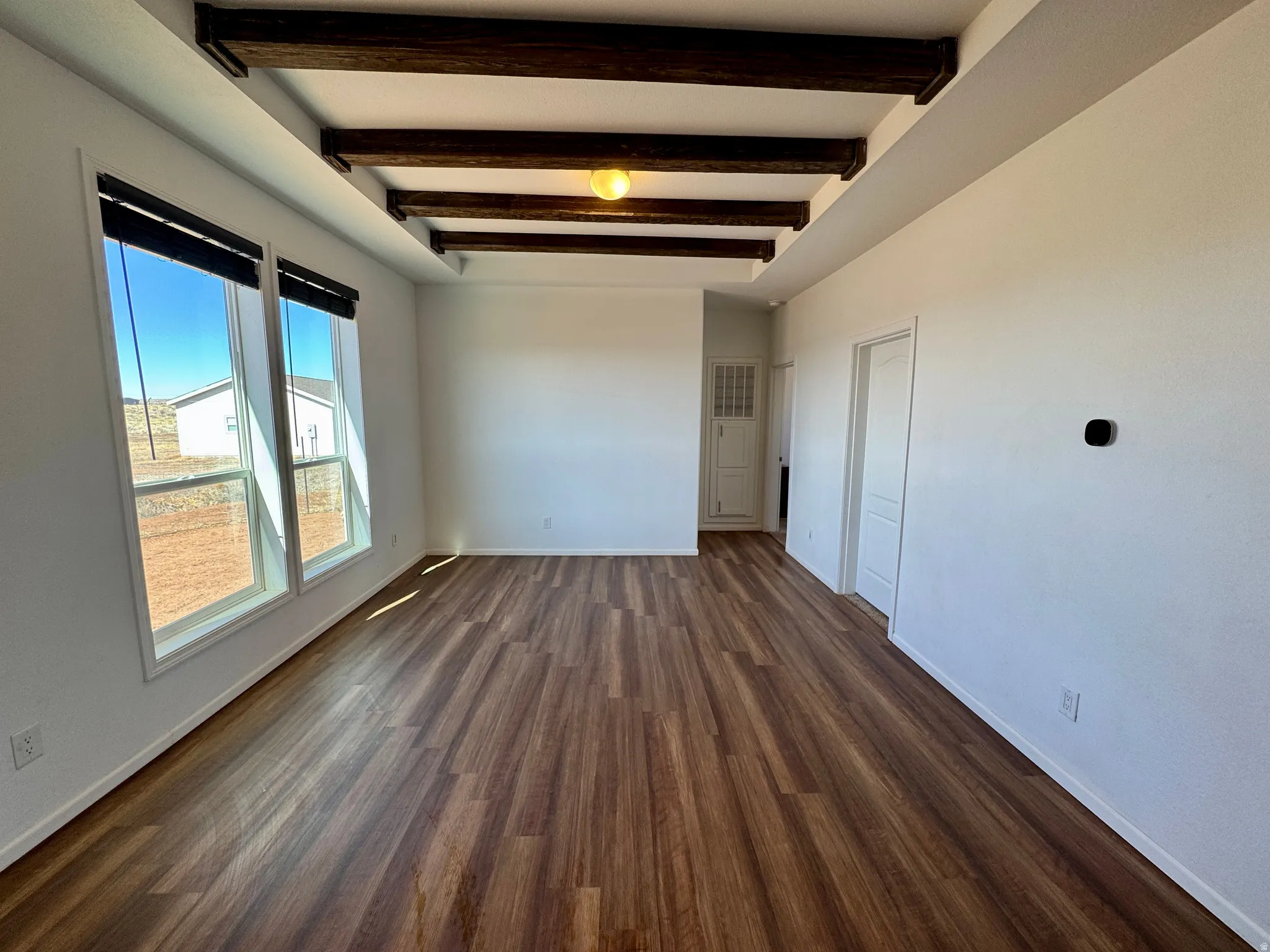Unfurnished room featuring beamed ceiling and dark wood finished floors