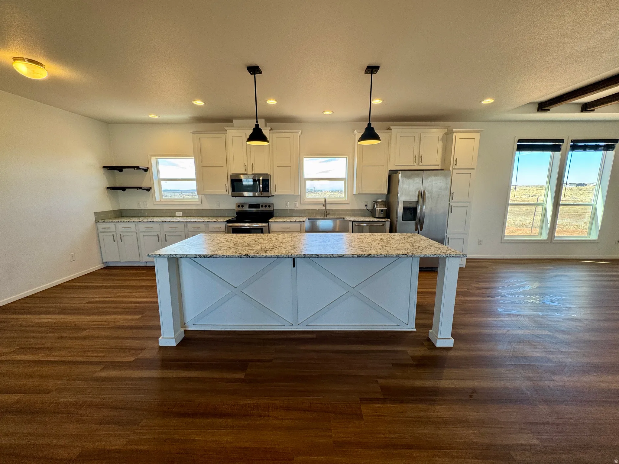 Kitchen featuring white cabinetry, decorative light fixtures, stainless steel appliances, and dark wood-style floors