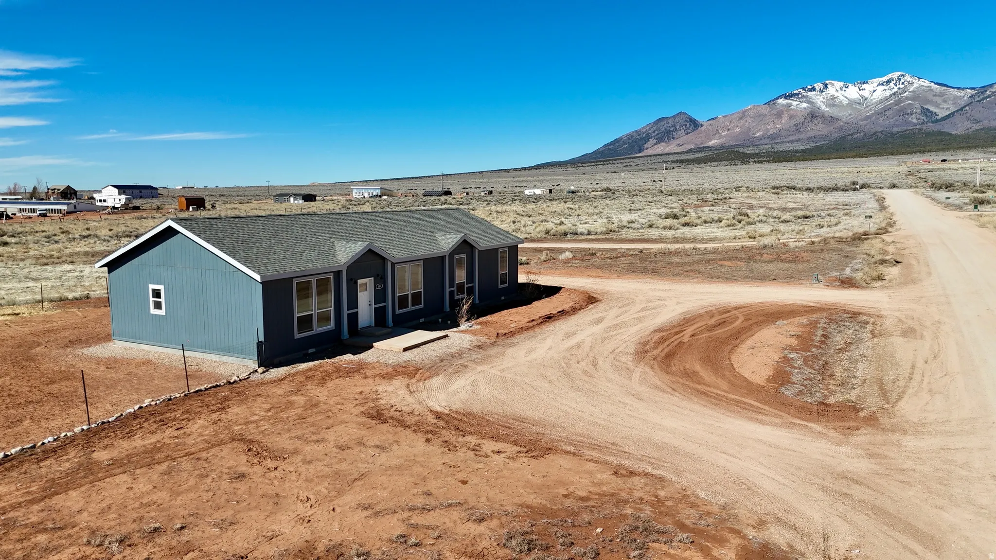 View of front of property with a mountain view, a shingled roof, a porch, a view of rural / pastoral area, and view of desert landscape