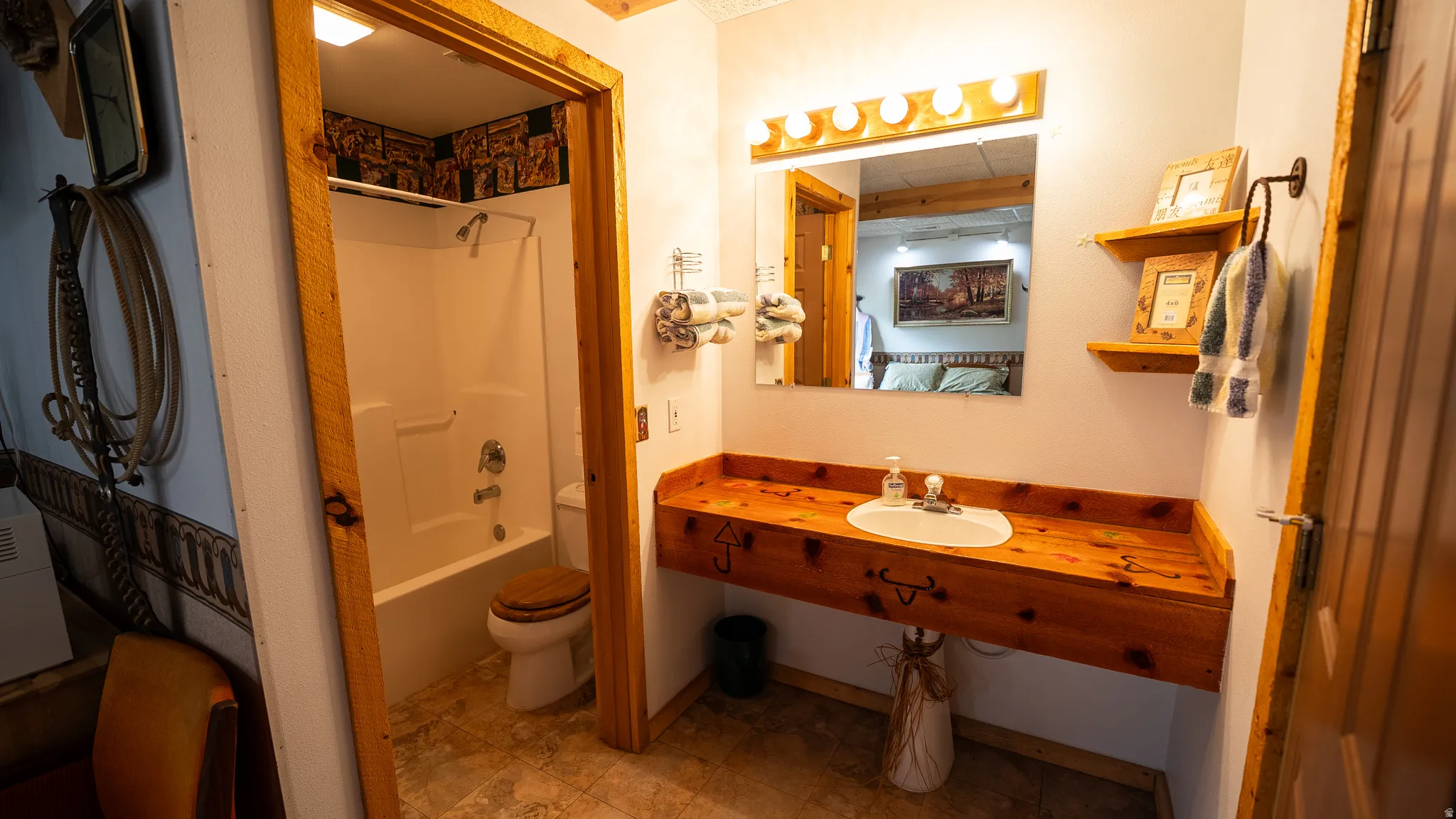 Bathroom featuring a wood-finish vanity with an integrated sink, a built-in tub/shower combination, and tiled flooring