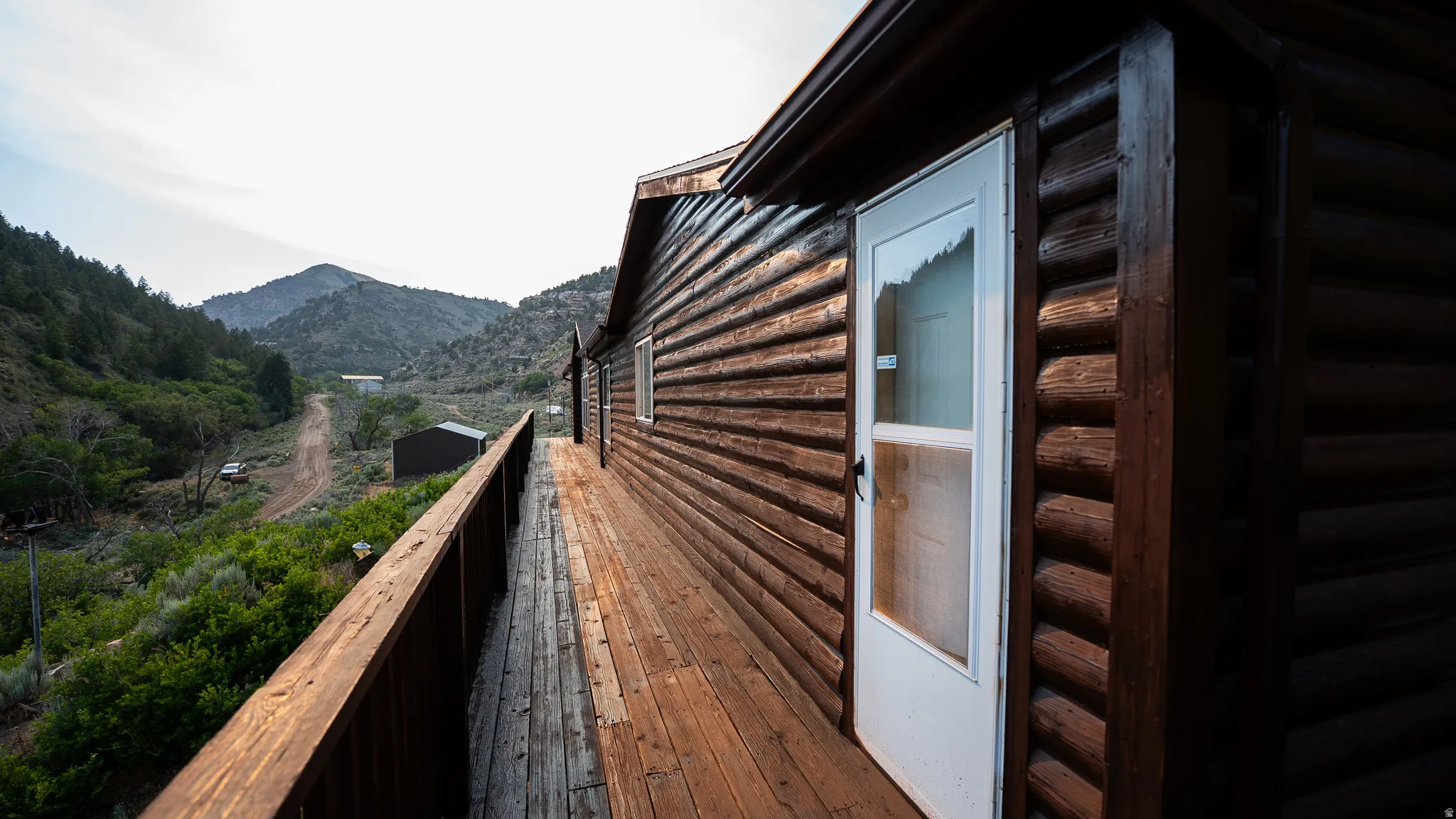 Expansive wood-finish deck with a wood railing, spanning the length of a log-style exterior