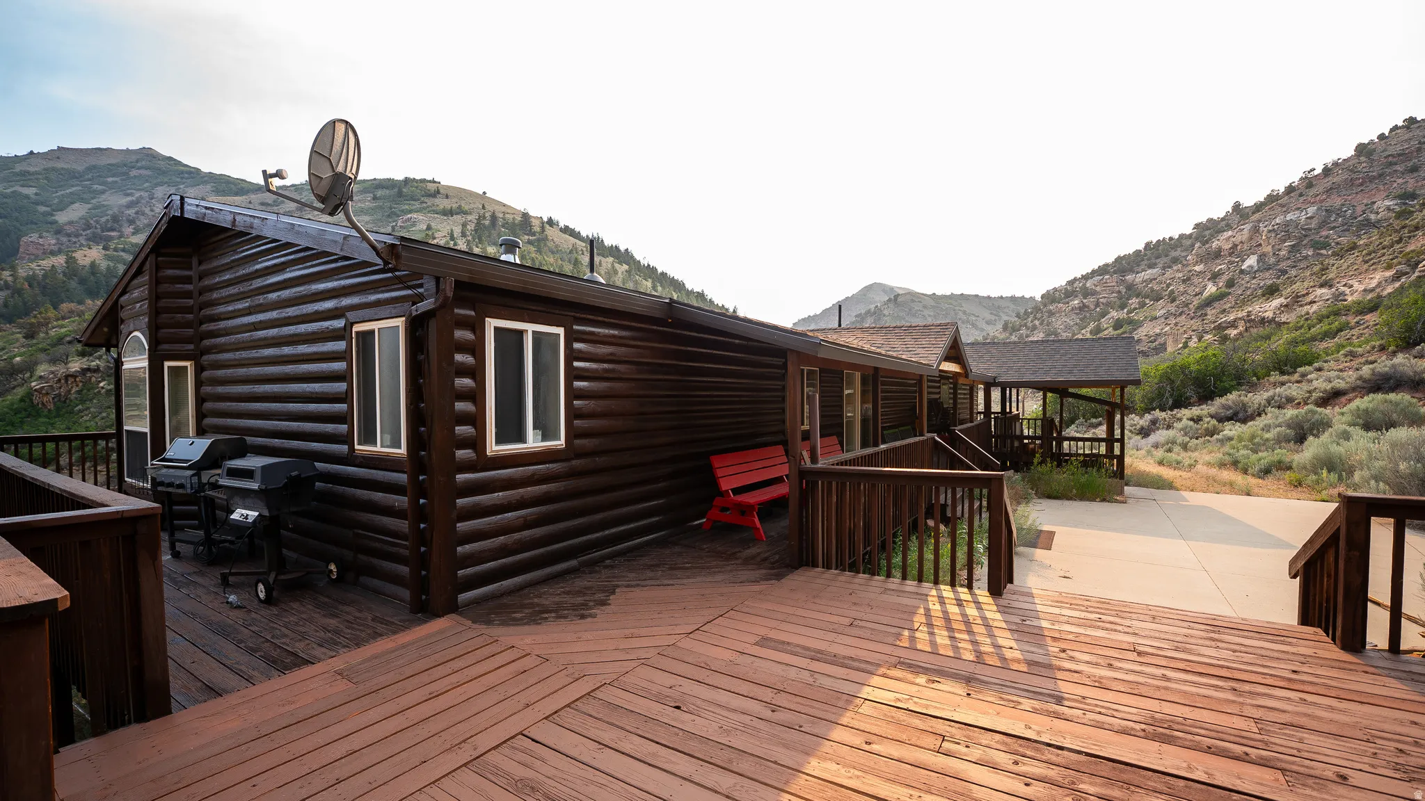 Expansive outdoor deck featuring wood flooring and railings, surrounding a log-style exterior