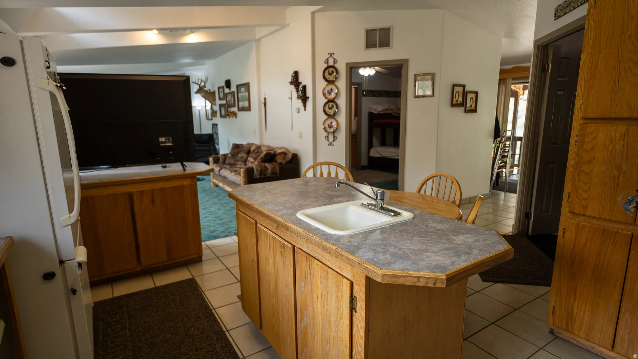 Kitchen island with an integrated sink and breakfast bar seating, showcasing wood-finish cabinetry and a light-toned countertop