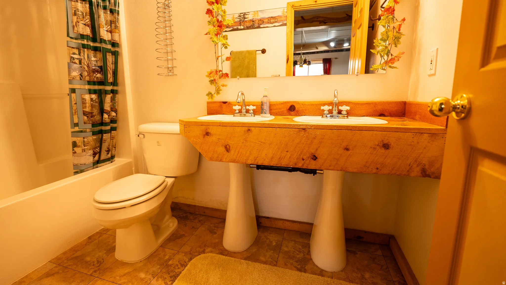 Bathroom vanity featuring a rustic wood countertop with dual sinks and pedestal bases
