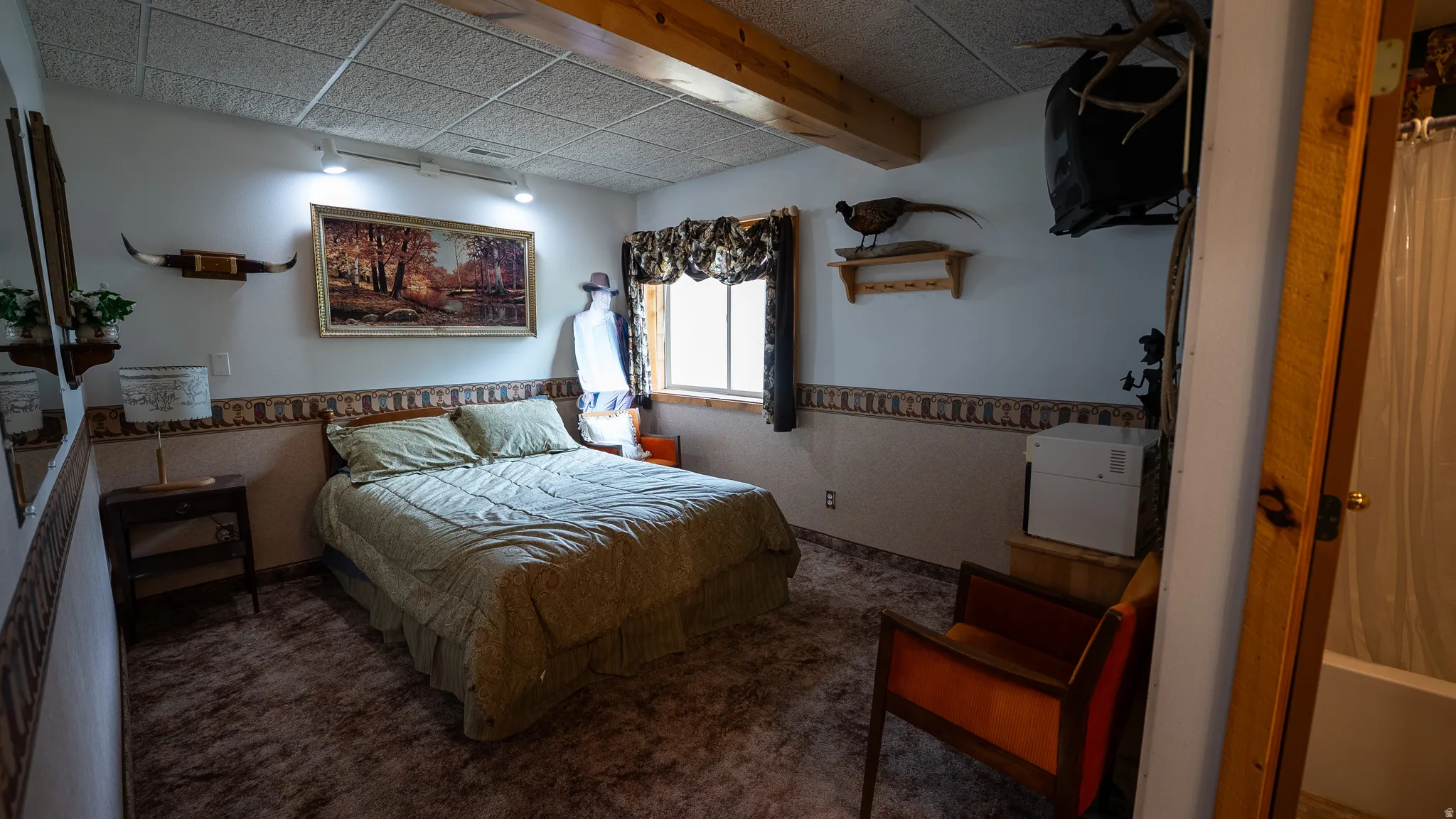 Carpeted room featuring exposed wood beams and track lighting