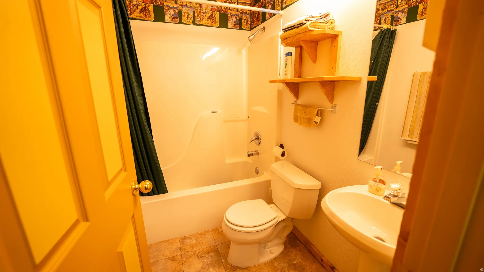 Bathroom featuring a white bathtub/shower combination, a wall-mounted sink with a chrome faucet, and a toilet
