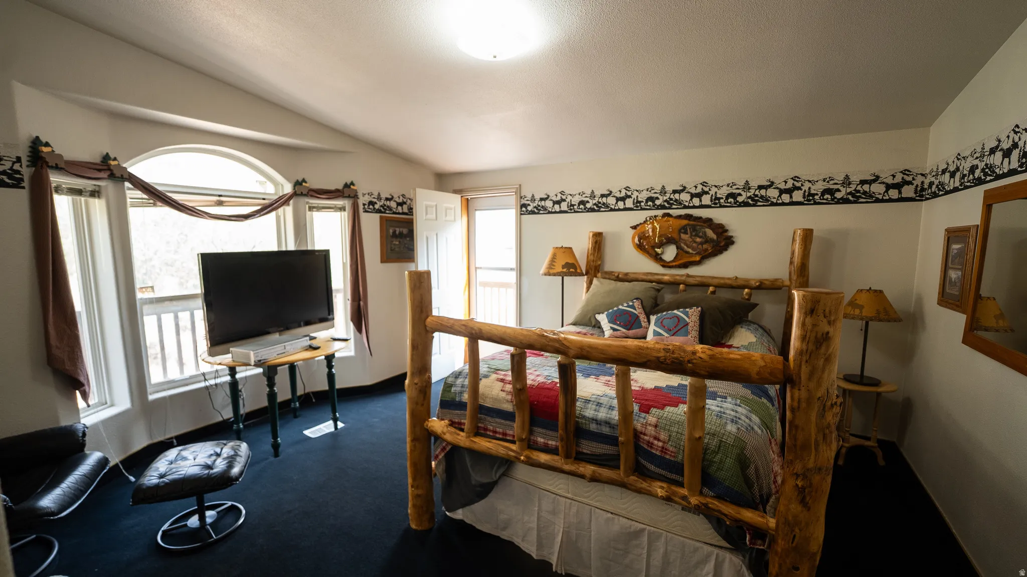Room featuring an arched window, a private exterior door, and dark carpeting