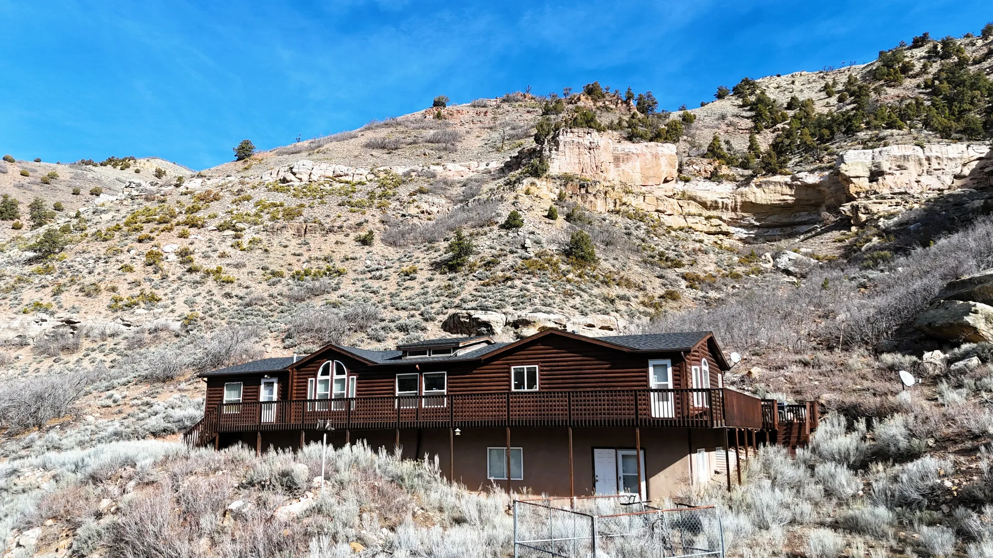 Back of property featuring a mountain view, log veneer siding, and roof mounted solar panels