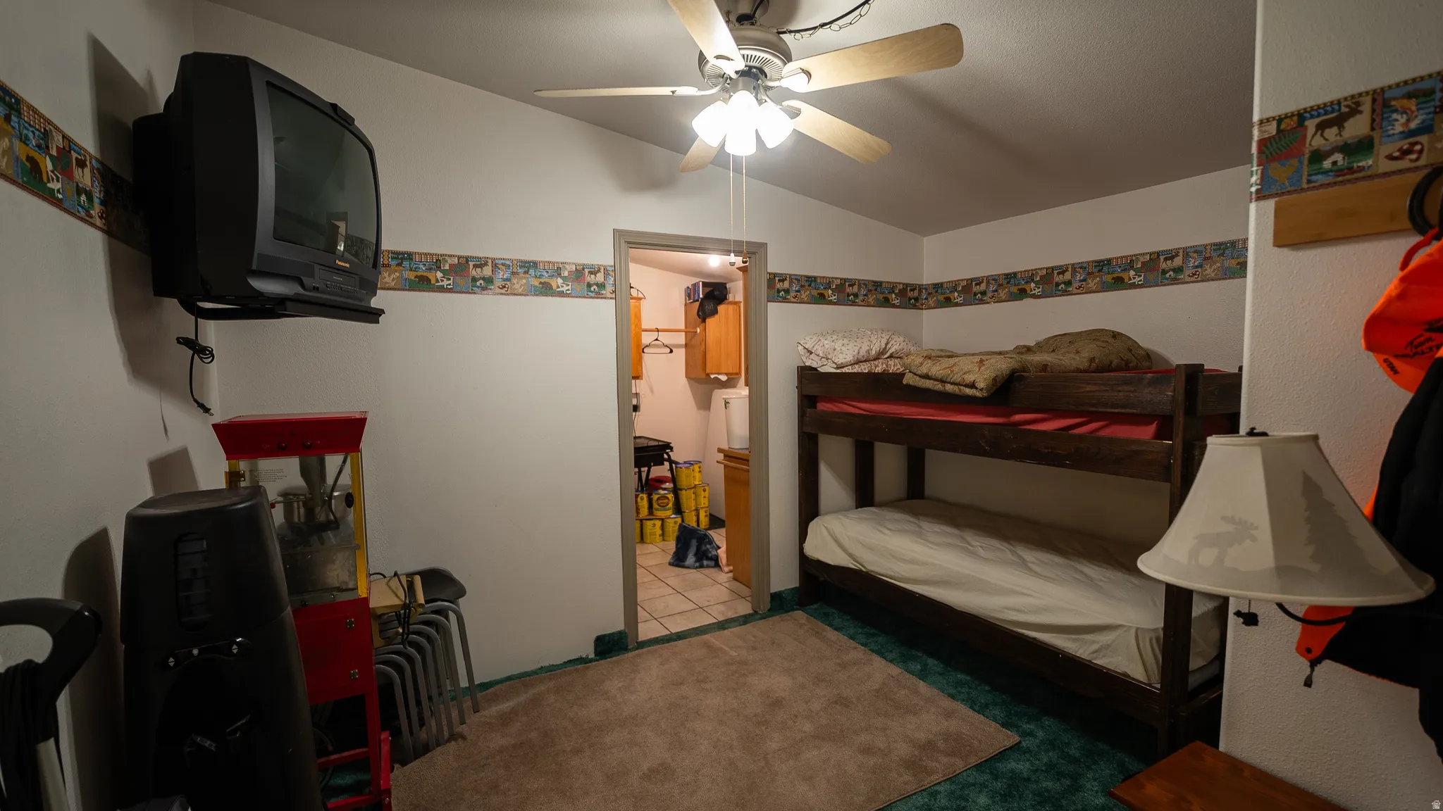 Room featuring a bunk bed, ceiling fan, and wall-mounted television