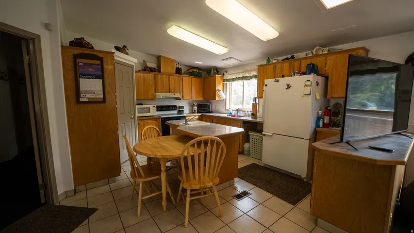 Kitchen featuring extensive light wood cabinetry, white appliances, and tiled flooring
