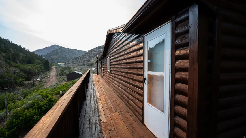 Expansive wood-finish deck with a wood railing, spanning the length of a log-style exterior