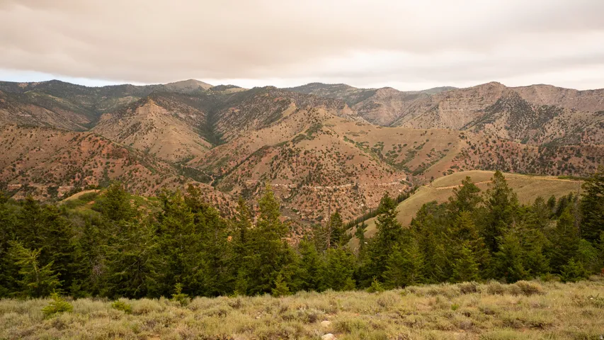 Expansive mountain scenery featuring rugged terrain, varied elevations, and distant peaks under a cloudy sky