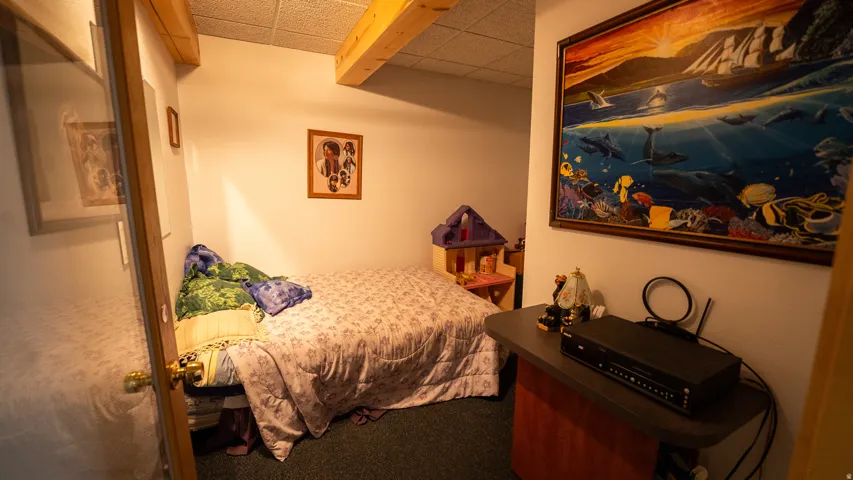 Carpeted room featuring exposed wood ceiling beams and a drop ceiling
