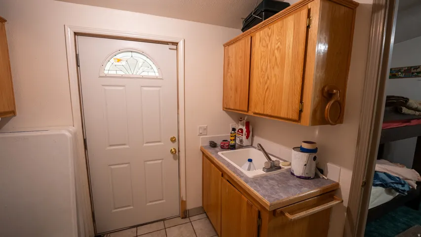 Utility area with wood cabinetry, an integrated sink, and laminate countertops