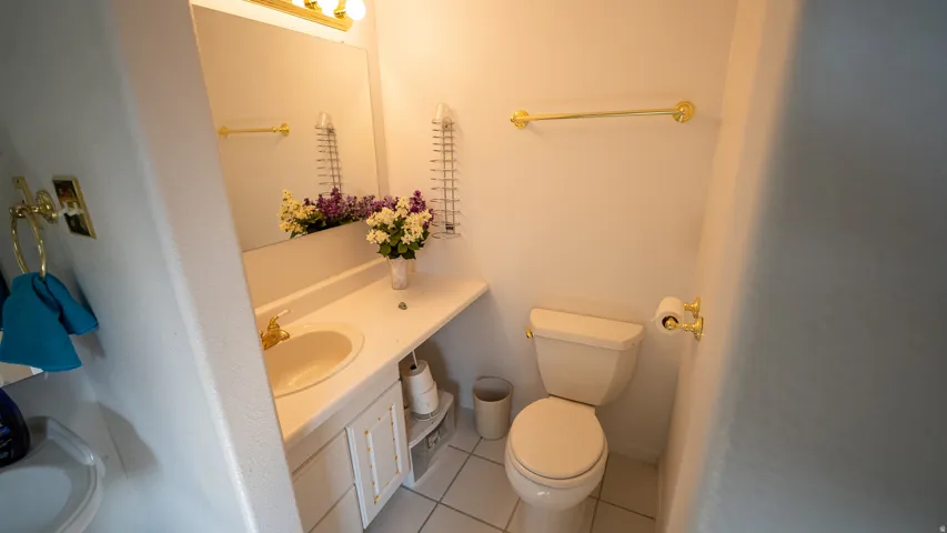 Compact powder room featuring a single vanity with an integrated sink, a large wall-mounted mirror, and gold-tone hardware