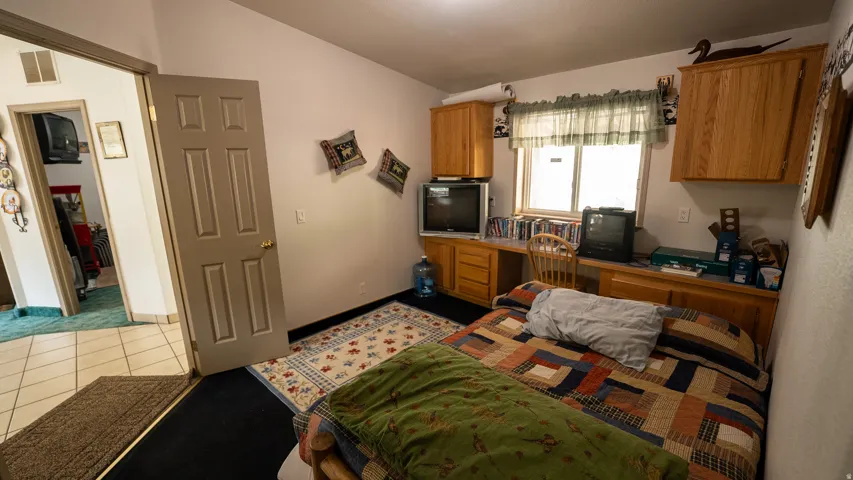 Room featuring a built-in desk with overhead cabinetry, a window with a valance, and a six-panel interior door