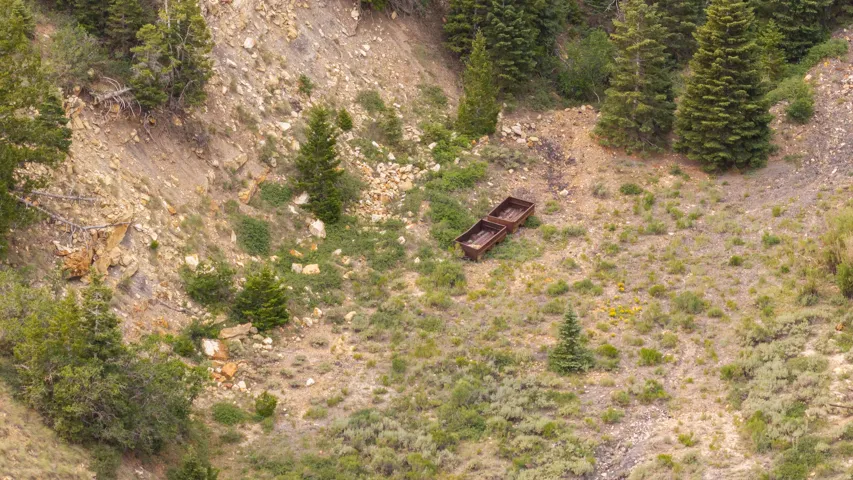 Sloping hillside terrain featuring two rustic mining carts