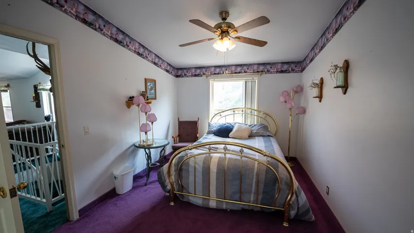 Bedroom featuring a ceiling fan, a window, and purple carpeting