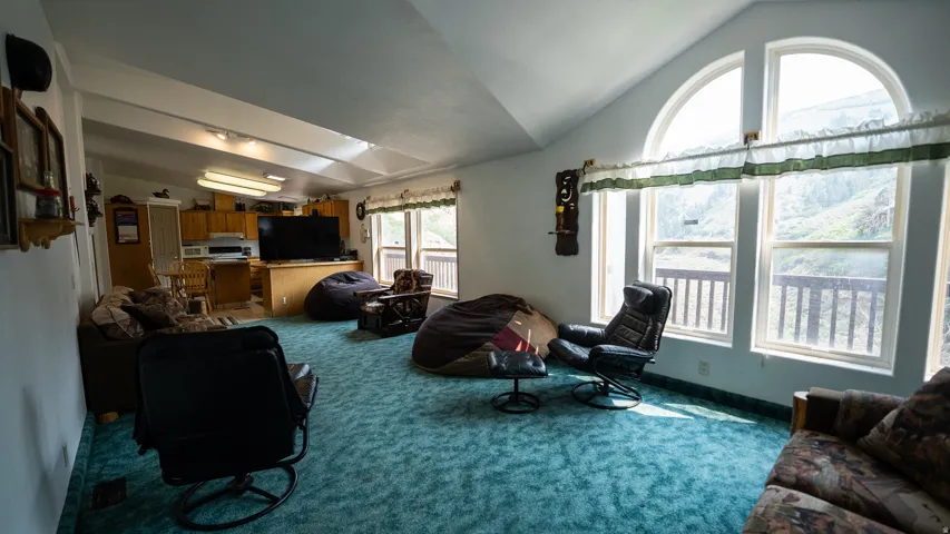 Spacious living area featuring vaulted ceilings and a wall of windows, including a large arched window