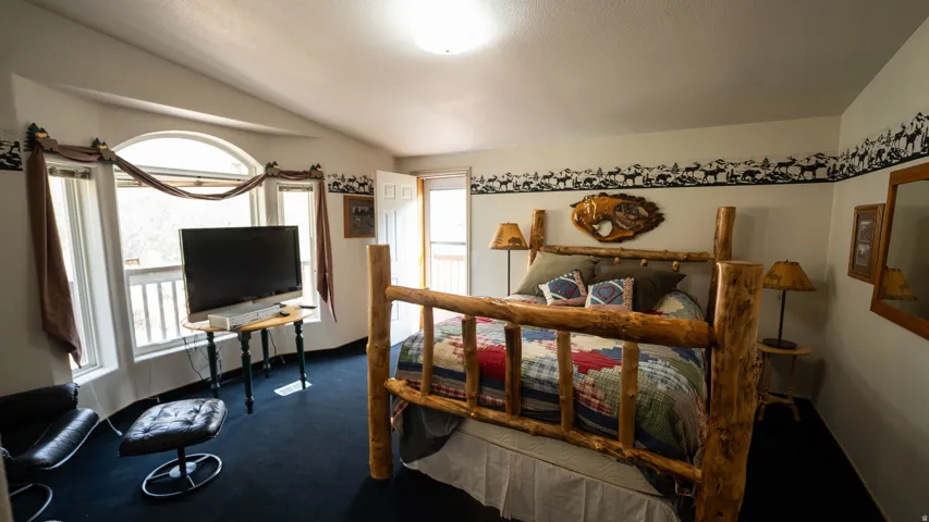 Room featuring an arched window, a private exterior door, and dark carpeting
