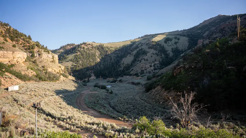 Expansive mountain landscape featuring varied terrain, a dirt road, and scattered structures