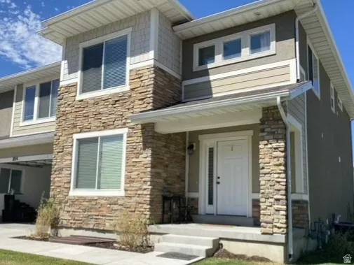 View of front of house featuring stone siding, a front yard, a garage, and concrete driveway