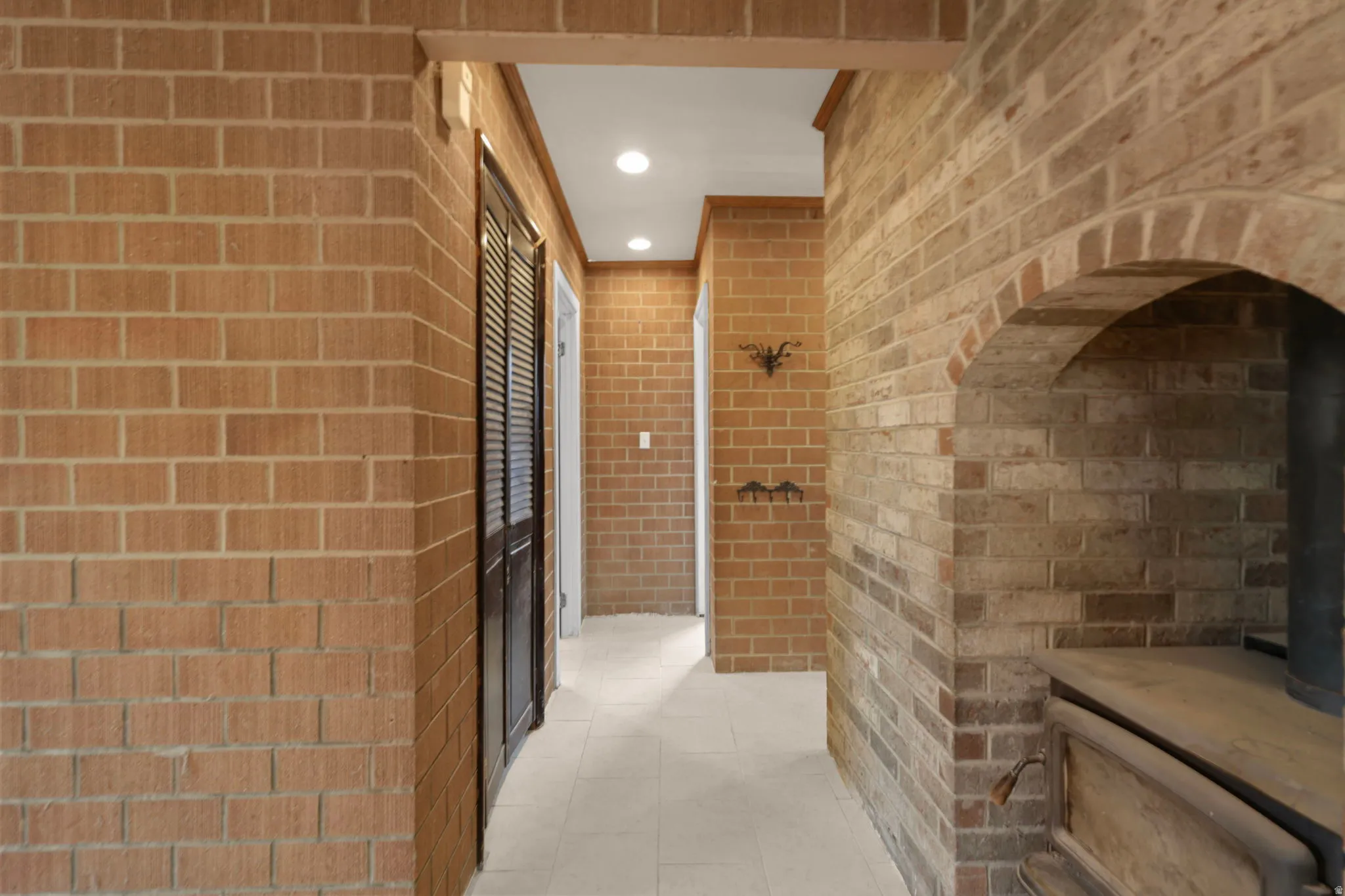 Full bath featuring recessed lighting, brick wall, a tile shower, and light tile patterned floors